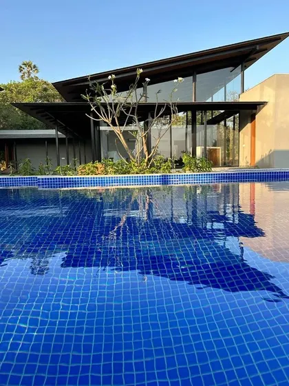 The sharp, angular roof of Villa 15 is reflected in the deep blue of the pool. These country homes are experiments in tropical architecture, simple and unadorned, ready to absorb the life lived within them.