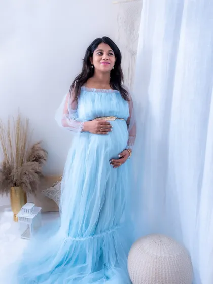 A candid-style lifestyle portrait in our studio. The mom-to-be looks happy and relaxed in a light blue gown.