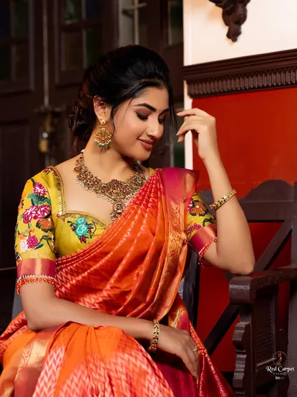 Actress Ragini Prajwal looking radiant for Day 1 of 'Navataara'. She is wearing an orange ikat silk saree with a custom yellow blouse featuring multi-color floral embroidery.