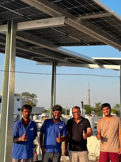A customer gives a thumbs-up alongside our crew after a successful solar panel installation on his terrace.