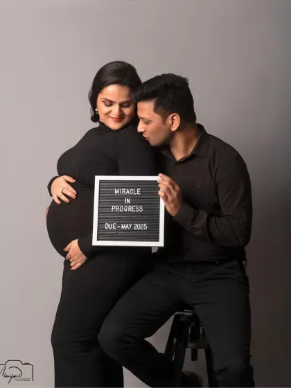 A sweet and intimate moment, with the partner whispering to the baby bump. The simple black outfits and grey background are modern and timeless.