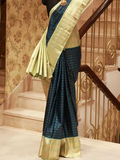 A stunning Kanjivaram with a checked teal body and a plain gold tissue border, a perfect blend of classic and contemporary design.