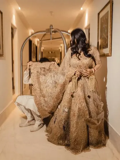 A fun, candid moment in a hotel hallway where the groom playfully hides behind the bride's lehenga. It's these unscripted moments that make a wedding story unique.