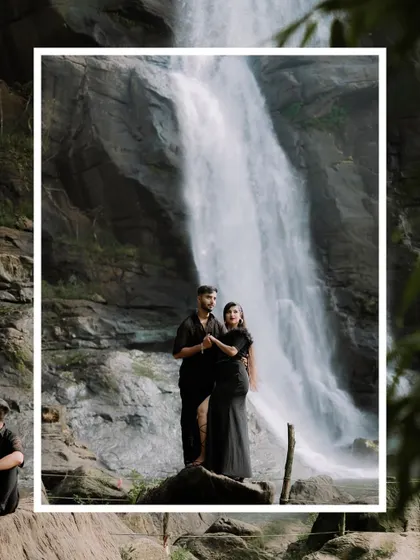 A creative shot of a couple posing by a waterfall, framed for artistic effect.