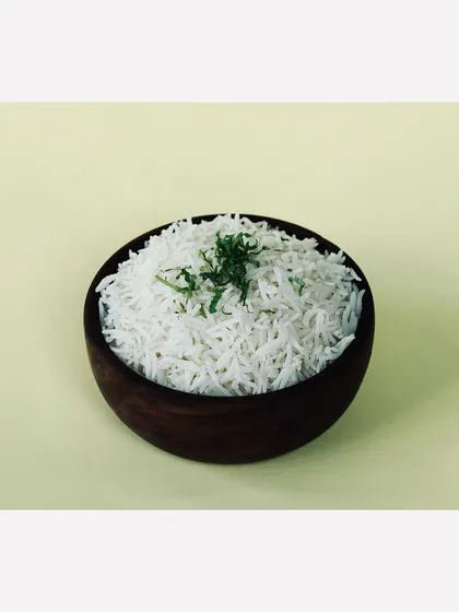 A simple bowl of steamed basmati rice against a pale yellow background. Even basic items are shot professionally to ensure a consistent, high-quality look across the entire menu.