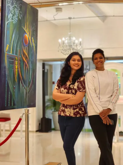 The artist with a guest next to her painting 'Intertwined Tale' at her solo exhibition.