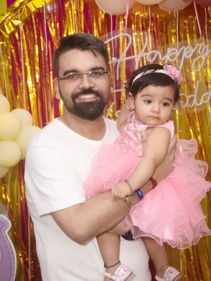 A father holds his daughter in front of a festive, shimmering backdrop at her party. Our event photography captures the bright and colorful details of your celebration.