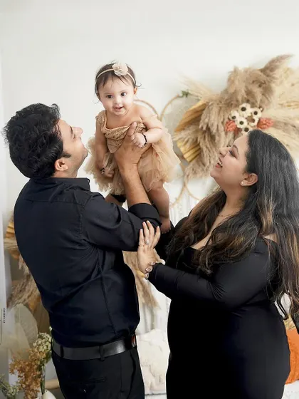 A candid and joyful family moment. The father lifts his daughter, and the mother's laugh makes this a wonderfully authentic and happy portrait.