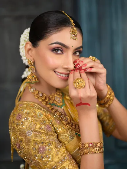 A playful and happy portrait of the South Indian bride. Her smile is radiant, and the makeup enhances her joyful expression with a warm, golden glow.