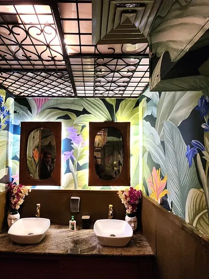 The vanity area of the washroom, where the botanical mural serves as a stunning backdrop for the mirrors. Even functional spaces can become works of art.