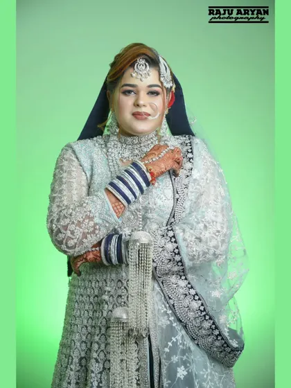 A classic three-quarter portrait against a studio backdrop. This image clearly shows the details of the bride's attire, makeup, and jewelry.