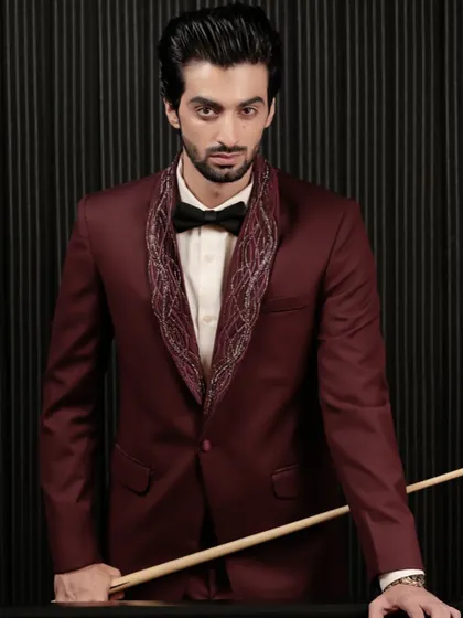 A powerful portrait in our burgundy tuxedo. The embroidered lapel draws the eye, making it a perfect choice for a groom's reception or a high-fashion event.