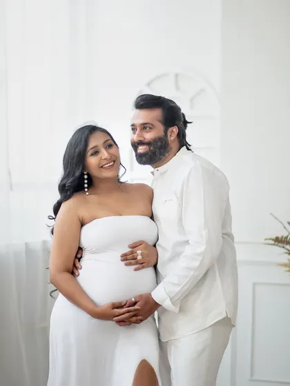 A candid, happy moment between the couple. The genuine smiles and loving gaze make this all-white studio shot feel warm and authentic.