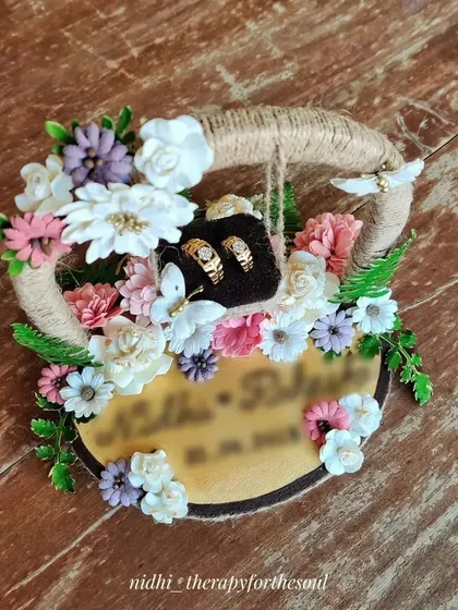 A close-up of the engagement ring platter, highlighting the detail of the paper flowers and the personalized base.
