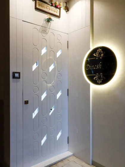 A custom safety door with a unique geometric pattern of circles and oblong shapes. The entrance is personalized with a backlit nameplate, creating a distinct identity for the home.