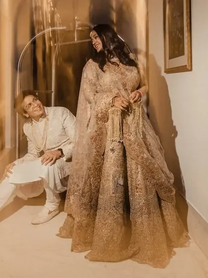 A beautiful portrait of the couple in the same hallway, showcasing their elegant wedding attire and the warm, luxurious ambiance of the location.