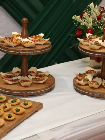 An elegant display of appetizers on tiered wooden stands. This setup for a corporate event features a variety of canapés, ensuring there is a delightful bite for every guest.