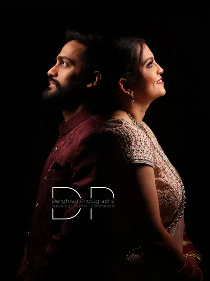A dramatic black and white studio-style portrait. The couple is posed back-to-back, looking upwards, creating a powerful and artistic image.