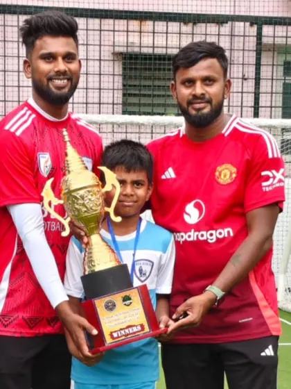 A young winner proudly holds the trophy alongside his coaches. This moment highlights the mentorship and guidance that is central to our academy's philosophy.