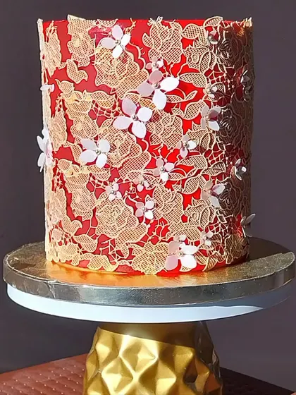 Cake decorating is an art form. This regal red cake, adorned with intricate edible gold lace and delicate wafer paper flowers, showcases the advanced techniques you can master in my specialized workshops.