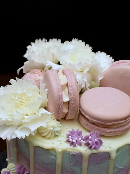 A detailed shot of the textured buttercream cake, showing the delicate white carnations nestled amongst pink macarons. It’s a perfect combination of flavors and textures.