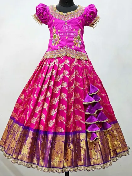 A mannequin view of the pink and purple lehenga with side ruffles. The puff sleeves and scalloped hemline of the blouse add to its designer appeal.