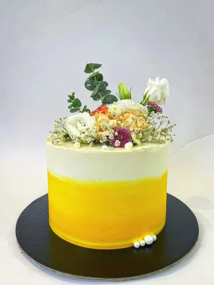 A simple yet stunning design perfect for a summer event. This single-tier cake has a beautiful yellow ombre buttercream finish, topped with a fresh and airy arrangement of white flowers and eucalyptus.