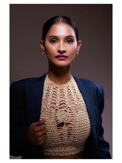 A powerful and confident portrait of a model in a blazer and crochet top. The strong lighting and direct gaze create a look of modern professionalism.