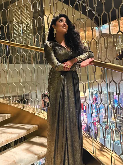 The full look of the solid gold gown, complete with a dramatic trail, making a statement on the staircase.