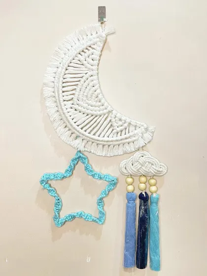 A celestial-themed wall hanging for a dreamy nursery. This piece features a macrame moon, a star, and a little rain cloud with colorful tassels, all hanging together.