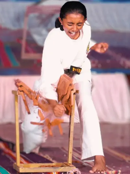 With a powerful kiai, this student executes a shuto uchi, or knife-hand strike, to break a stack of boards, proving that technique and spirit overcome brute force.