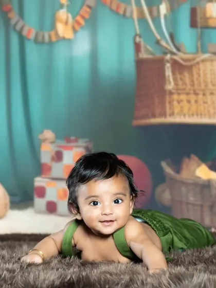This baby is enjoying the view from the ground, with the colorful hot air balloons above.
