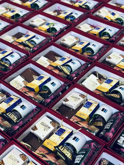 An angled shot of rows of open gift boxes, giving a clear view of the contents before they are sealed and shipped for a major corporate order.
