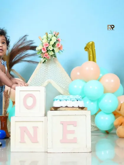 The birthday boy stands proudly next to his "ONE" blocks and cake. This shot captures a key milestone: standing and exploring on their first birthday.