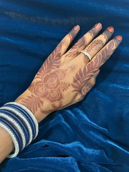 A simple yet elegant Eid henna design with a rose and leaf pattern. Paired with blue bangles, this shows how a minimal design can make a beautiful statement.
