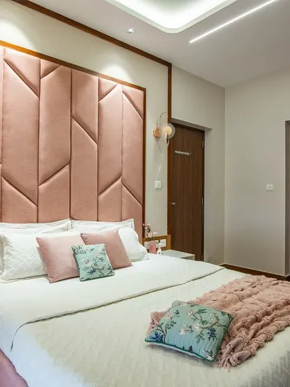Another view of the pink bedroom, highlighting the tall, dramatic headboard and the simple, clean lines of the floating nightstands. The design is both bold and elegant.