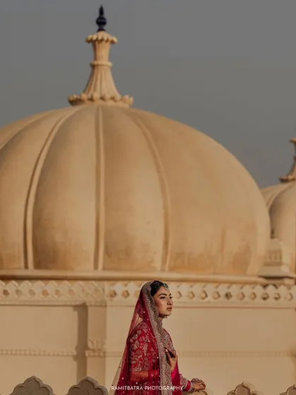 A bride poses against the iconic domes of The Oberoi Udaivilas in Udaipur, her portrait framed by timeless architecture.