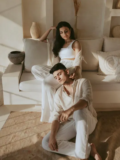 A tender and intimate portrait where he rests his head on her lap. The warm sunlight streaming in creates a soft, romantic mood, highlighting a moment of comfort and trust between the couple.