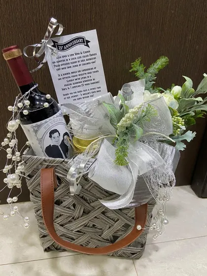 A personalized anniversary gift featuring a custom-labeled bottle of wine. Nestled in a stylish woven basket with floral accents and a heartfelt note, it's a truly personal way to celebrate a milestone.
