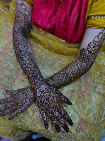 A beautiful crossed-hands pose showing the symmetry and artistry of the full bridal floral design.