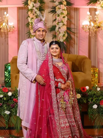 A full-length portrait of the bride and groom in front of their beautifully decorated wedding stage.