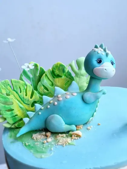 A close-up of the blue brontosaurus topper, showing the texture and details on its back.