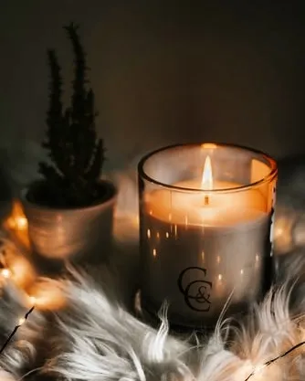 This is my classic C&C branded jar candle, creating a warm and inviting glow. Placed on a soft surface with fairy lights, it shows how a simple scented candle can transform your space into a cozy sanctuary.