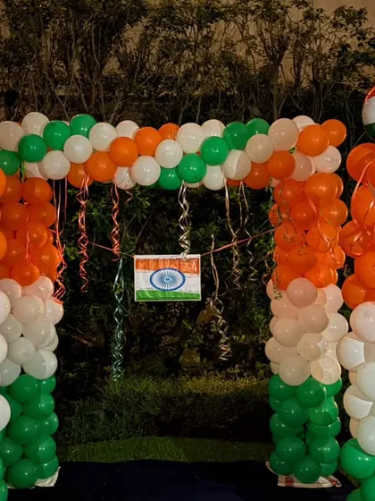 A balloon arch in the Indian tricolor, set up at night for an evening celebration of a national holiday.