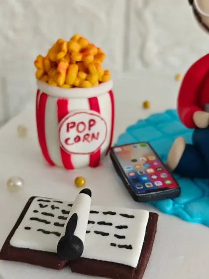 A closer look at the tiny, edible accessories on Ayush's cake, including a bucket of popcorn, a smartphone, and a book. It's these details that tell a story.