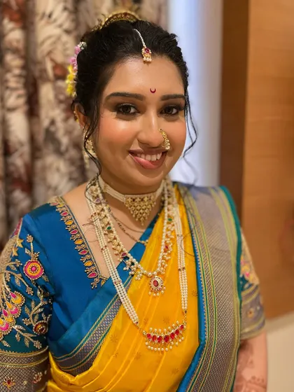 A stunning wedding look for bride Vijayalakshmi. The yellow and blue Paithani saree is complemented by intricate jewelry and flawless makeup.