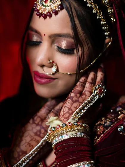 A serene portrait with the bride's eyes closed, showcasing her stunning eye makeup and the sparkle of her jewelry. This pose conveys a sense of calm and anticipation.