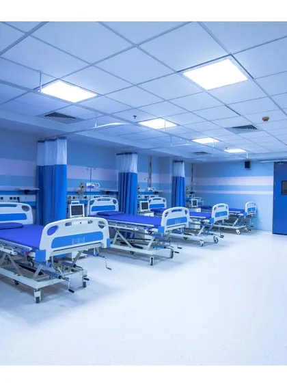 The post-operative recovery ward at Memorial Hospital and Research Centre in Kerala. The space is designed for cleanliness and function, with ample room between beds and a sterile, calming blue and white color scheme.