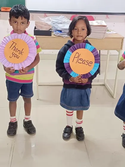 Four students proudly display their handmade signs for 'Excuse me', 'Thank you', 'Please', and 'Sorry', the magic words of polite conversation.