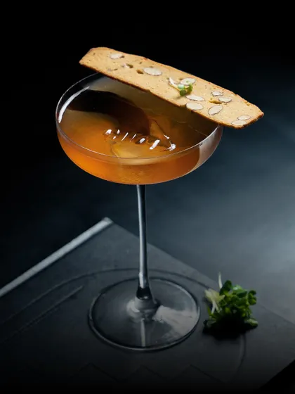 This is our 'Nilgiri' cocktail, a unique blend of smokey whiskey, coffee, eucalyptus, lavender milk, and vermouth, served with an almond biscotti.